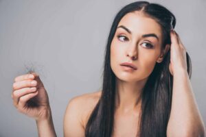 young woman looking into mirror at her receding hairline