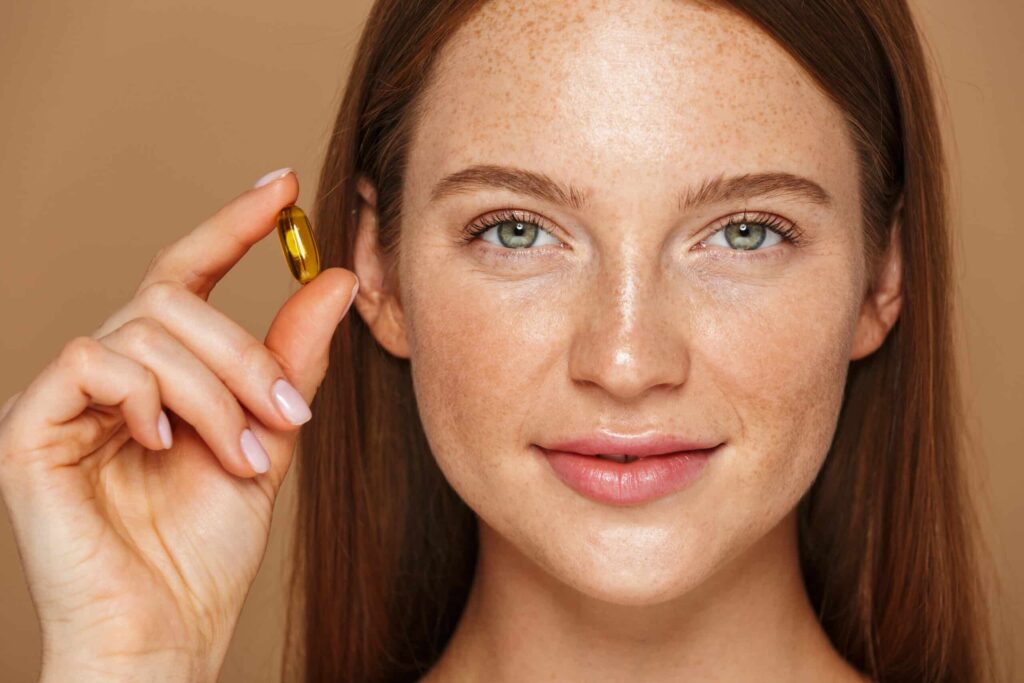 Young woman with long hair holding up a gel capsule supplement