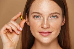 Young woman with long hair holding up a gel capsule supplement