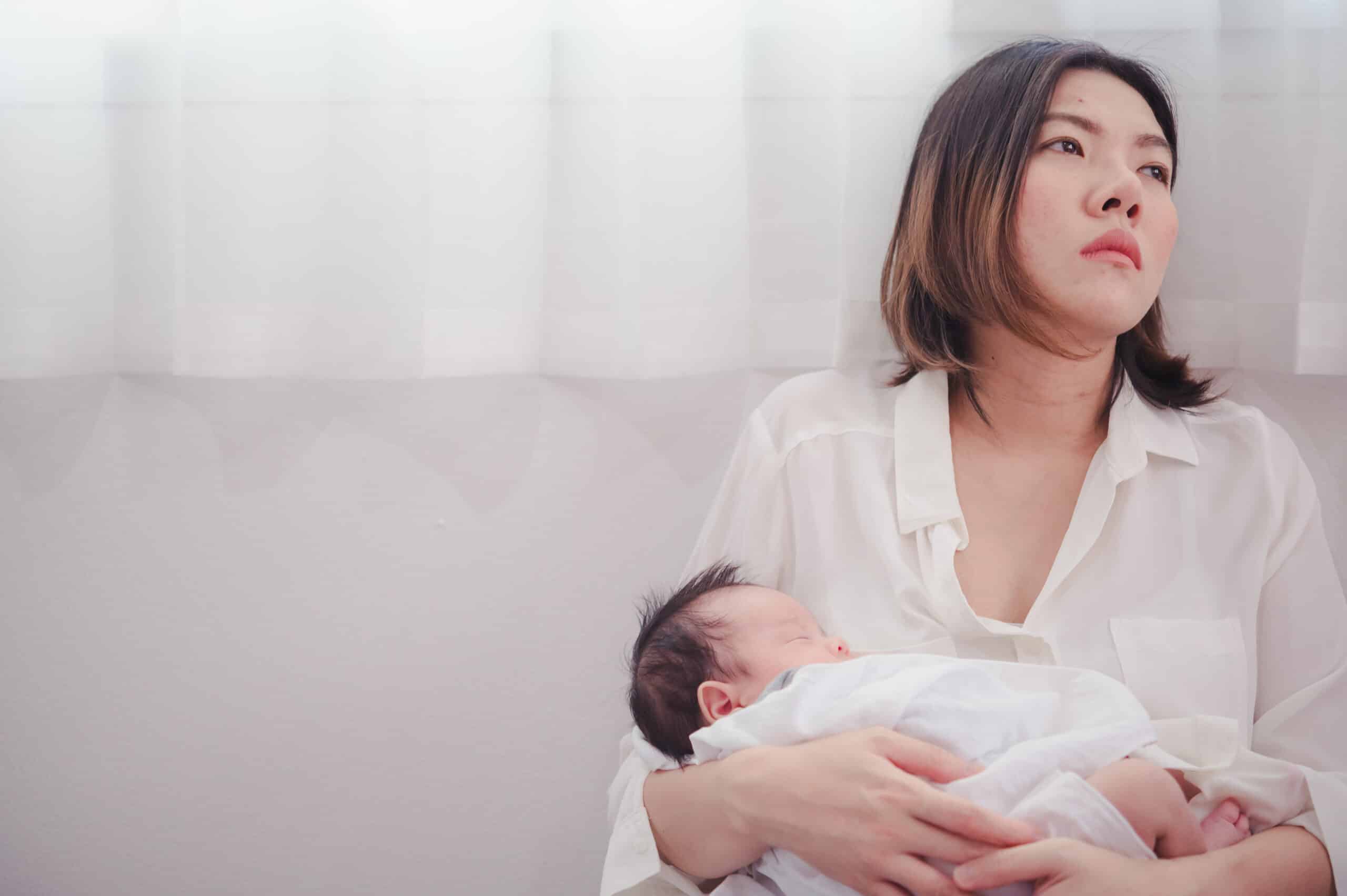 tired woman with black hair holding newborn baby