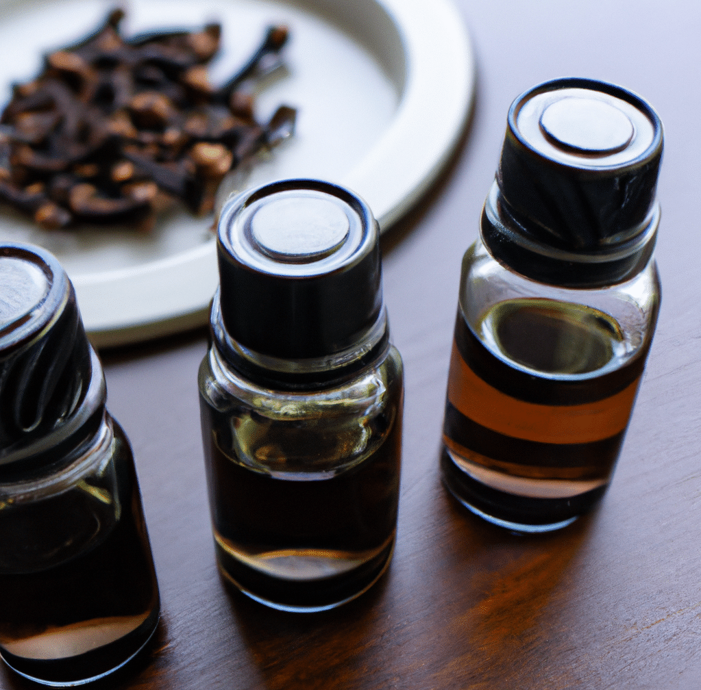 bottles of clove essential oil on table next to a bowl of cloves